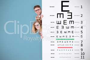Composite image of geeky hipster holding poster and smiling at c