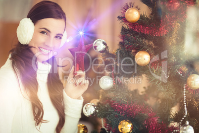 Smiling brunette holding star near a christmas tree