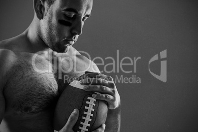 Composite image of shirtless american football player with ball