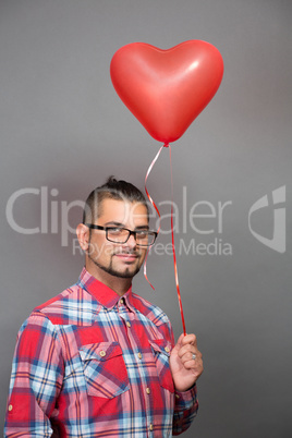 Handsome hipster man with red heart baloon in studio