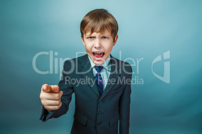 European appearance teenager boy in a business suit points a fin