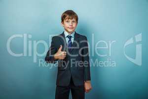 European appearance teenager boy in a business suit shows a sign