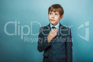 European appearance teenager boy in a business suit straightens