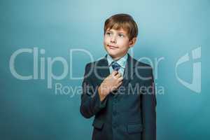 European appearance teenager boy in a business suit straightens