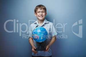 European appearance teenager boy with glasses holding a globe on