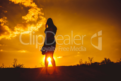 European appearance young woman standing at sunset looking at th