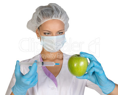 Woman holding an apple and is injected with a syringe. Genetically modified foods