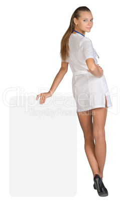 Young woman doctor standing backward, leaning hand on an empty billboard