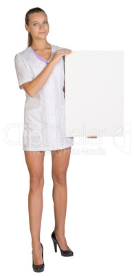 Woman doctor showing blank billboard standing on a white background