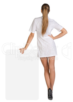 Young woman doctor standing backward, leaning hand on an empty billboard