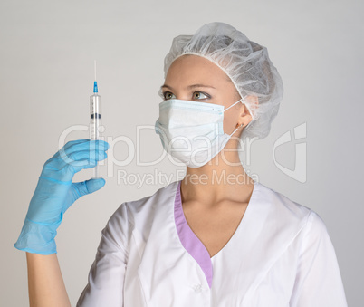 Doctor a masked holds before him syringe in hand