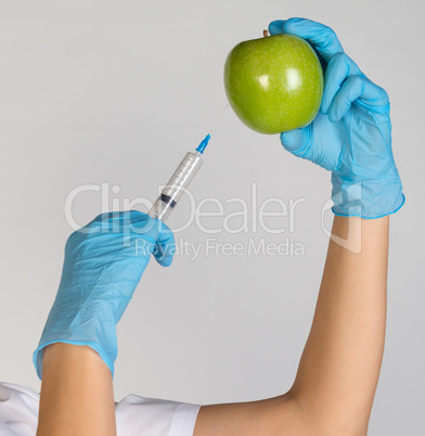 Woman holding an apple and is injected with a syringe. Genetically modified foods