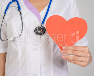 Female doctor with stethoscope holding a red paper heart