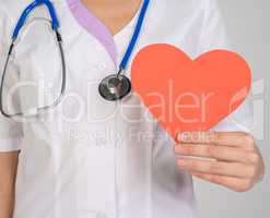 Female doctor with stethoscope holding a red paper heart