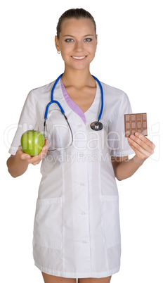 Woman doctor holding an apple and chocolate symbolize proper nutrition, diet