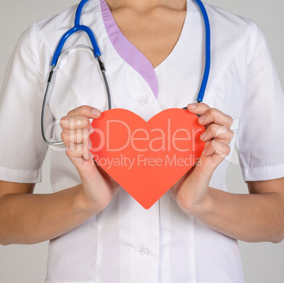 Doctor with stethoscope holding red paper heart