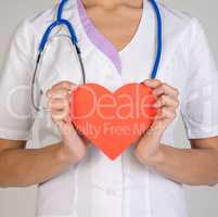 Doctor with stethoscope holding red paper heart