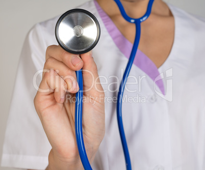 Woman doctor in lab coat holding stethoscope