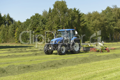 Agriculture, the kidding of shaken grass with blue tractor with