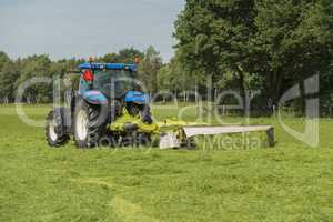 Agriculture, pasture mowing with blue tractor .