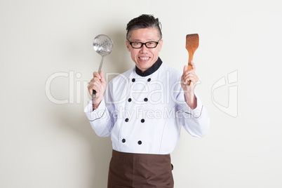 Mature Asian Chinese chef with kitchen tools