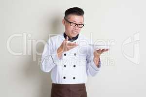 Mature Asian Chinese chef presenting dish