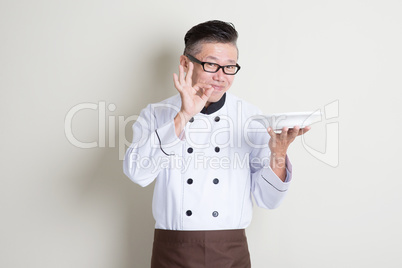 Mature Asian Chinese chef showing satisfied hand sign