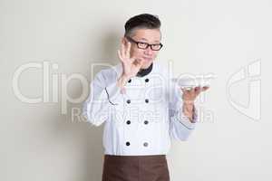 Mature Asian Chinese chef showing satisfied hand sign