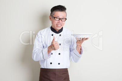 Mature Asian Chinese chef presenting dish and thumb up
