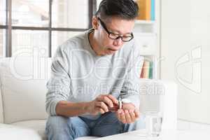 Mature 50s Asian Chinese man eating medicine