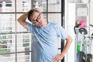 Mature Asian man stretching neck at gym