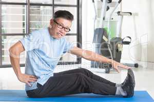 Mature Asian man exercising at gym