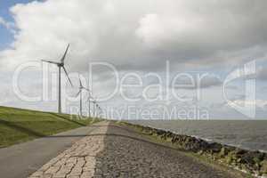 Modern windmills nearby the dike in the Netherlands