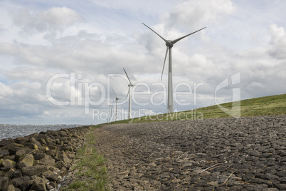 Modern windmills nearby the dike in the Netherlands