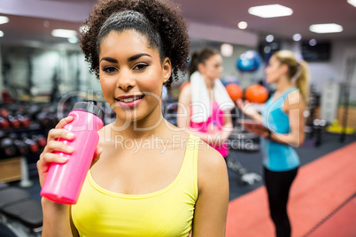 Fit woman smiling at camera in weights room