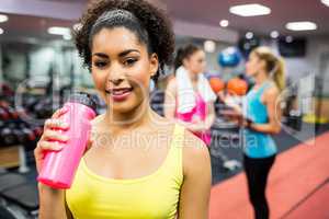 Fit woman smiling at camera in weights room