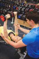 Woman lifting dumbbells with her trainer