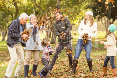 Happy extended family throwing leaves around