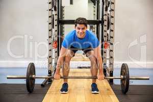 Smiling man about to lift a barbell