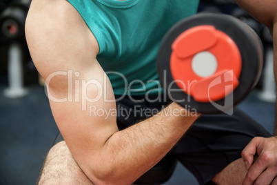 Man lifting dumbbell weight while sitting