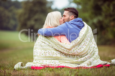 Happy couple sitting under blanket