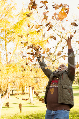Happy old man throwing leaves around