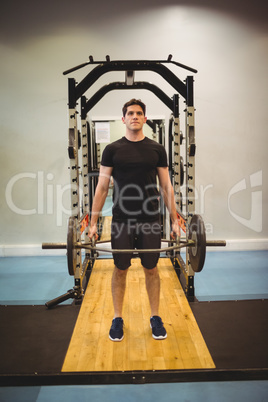 Fit man lifting heavy barbell