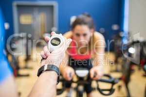 Woman on exercise bike with trainer timing her