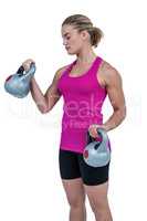 Muscular woman exercising with kettlebells