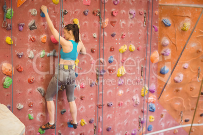 Woman climbing up rock wall