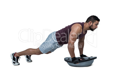 Muscular man doing bosu push ups