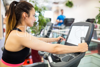 Woman using the exercise bike and looking at a small screen