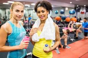 Fit women smiling at camera in weights room