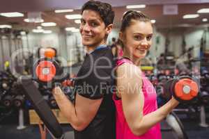 Fit couple lifting dumbbells together